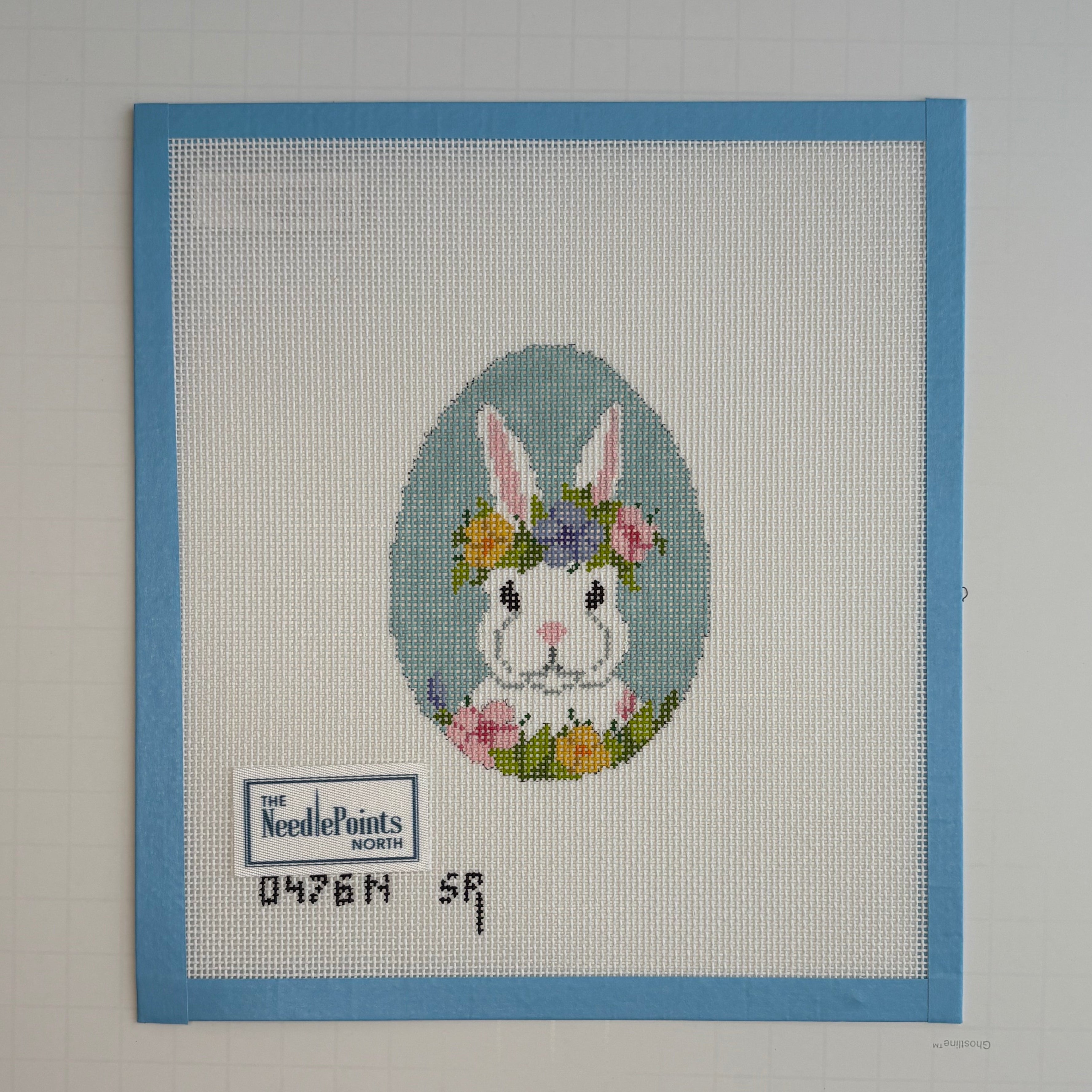 needlepoint bunny with flowers on a white background with blue border