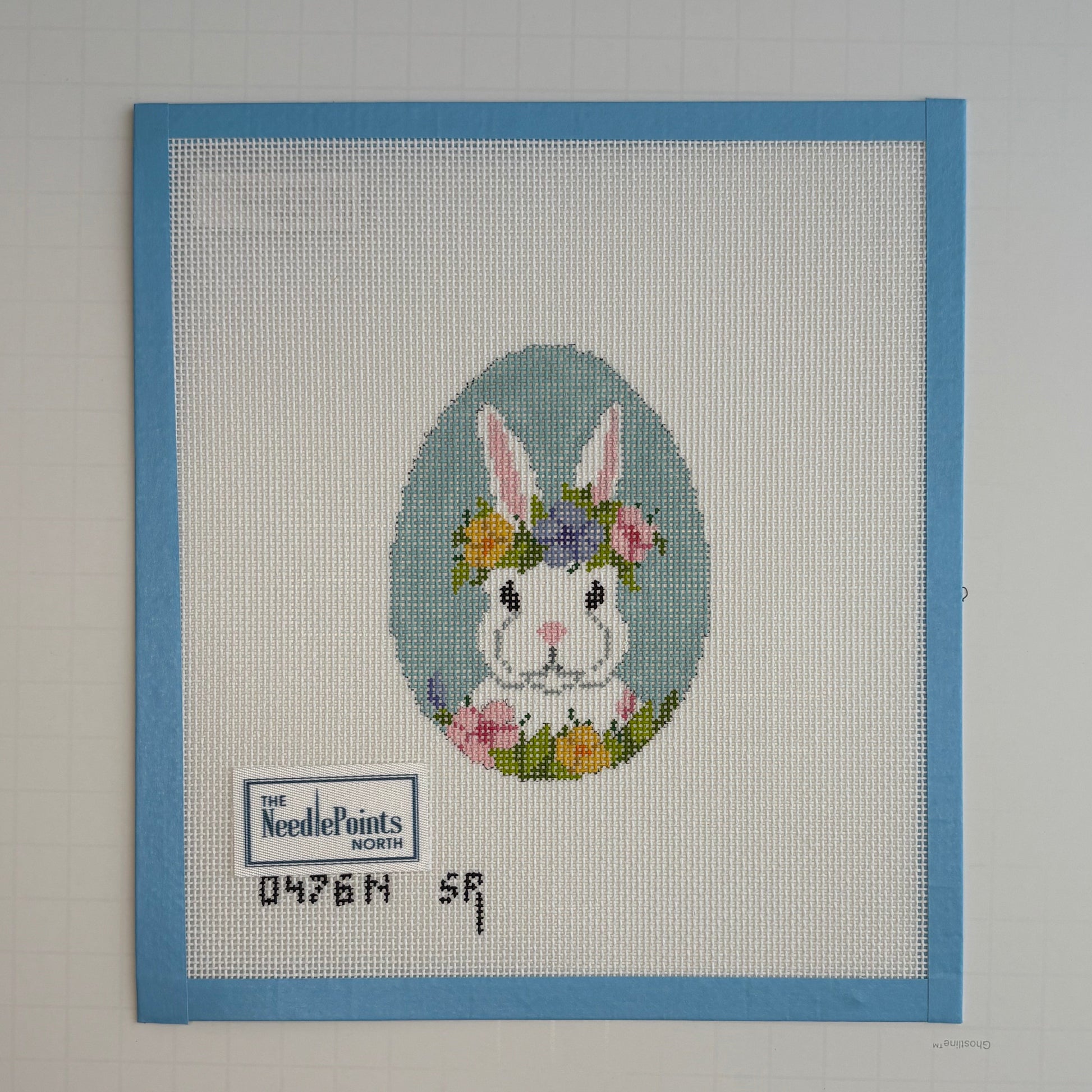 needlepoint bunny with flowers on a white background with blue border