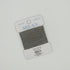 Gray thread on a Tilli Tomas Milan label against a light gray background