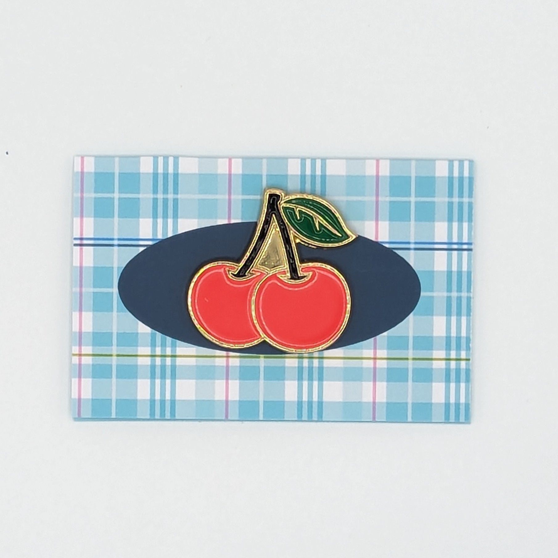 Rectangular placemat with cherry design on a plaid pattern against a light gray background