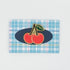 Rectangular placemat with cherry design on a plaid pattern against a light gray background