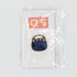 A small enamel pin shaped like a dark navy blue mouth with gold-tone teeth, mounted on a clear display card with a red and gold logo, photographed against a light gray background.
