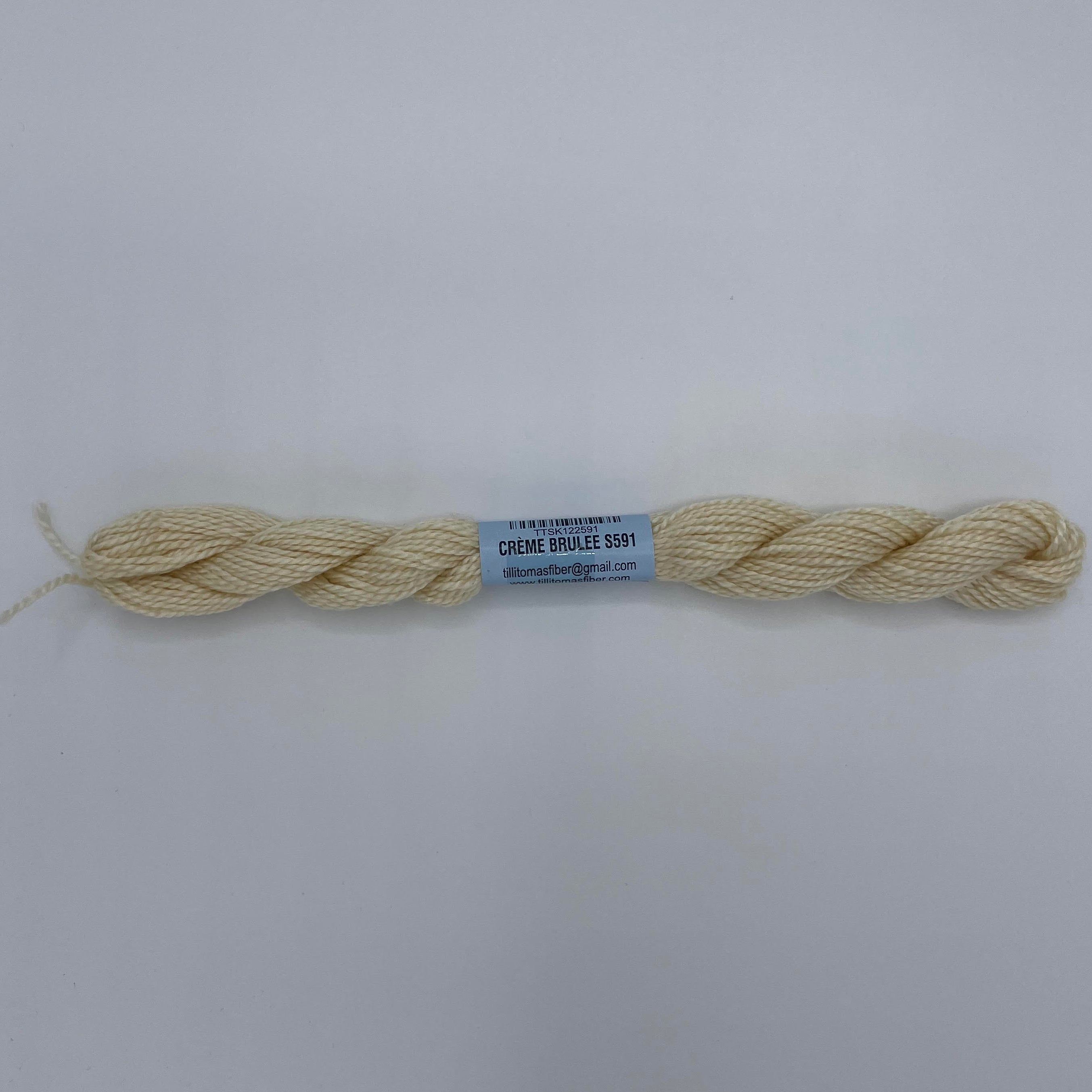 Ball of cream-colored yarn with a label on a white background