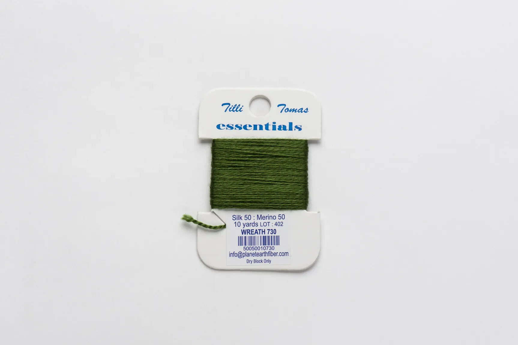 Green thread on a Tilli Tomaz essentials label against a white background